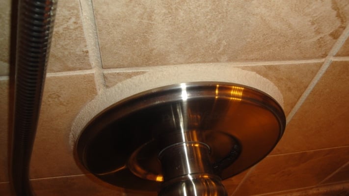 The image below shows the shower valve protruding from the wall tile which the tile "placer" filled in with grout. 