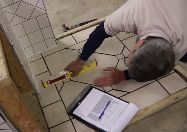 Scott checks the insert dots in the floor to make sure that they are flush with the floor tile both left and right and north and south.