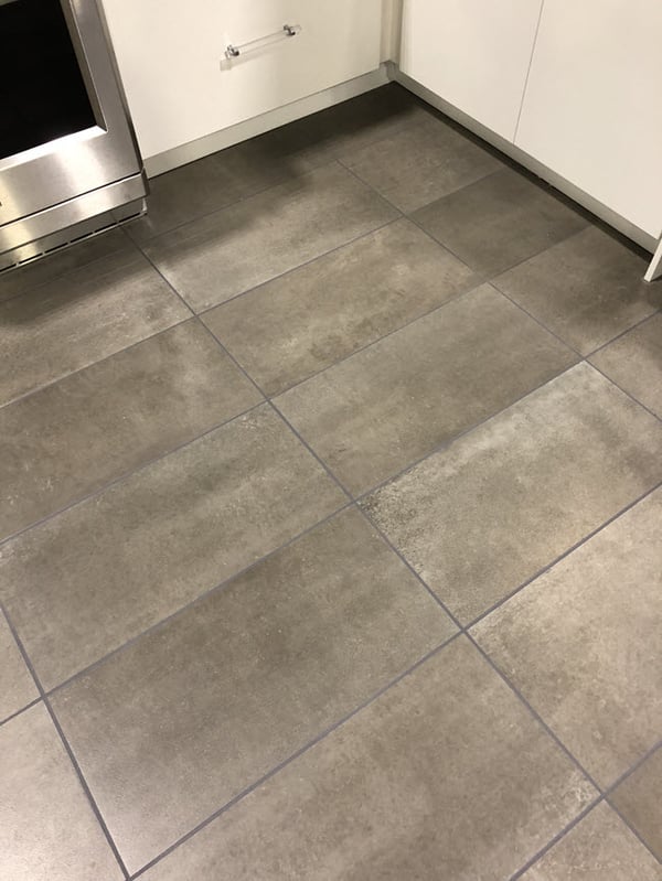 The floor features a large format cement look porcelain tile.